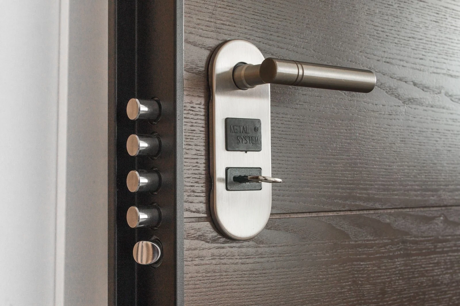 Close detail of a dark entry door with a long metal handle and lock